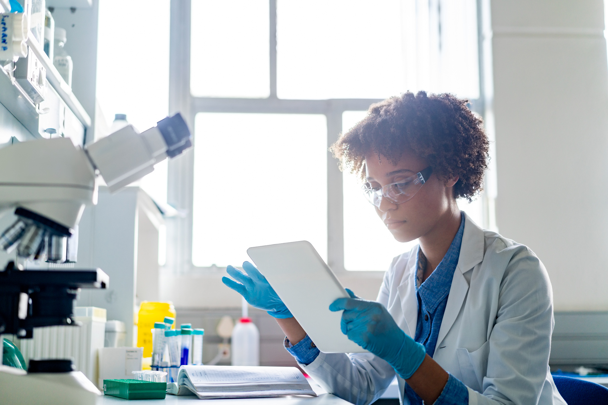 Young female scientist using digital tablet in lab to review data