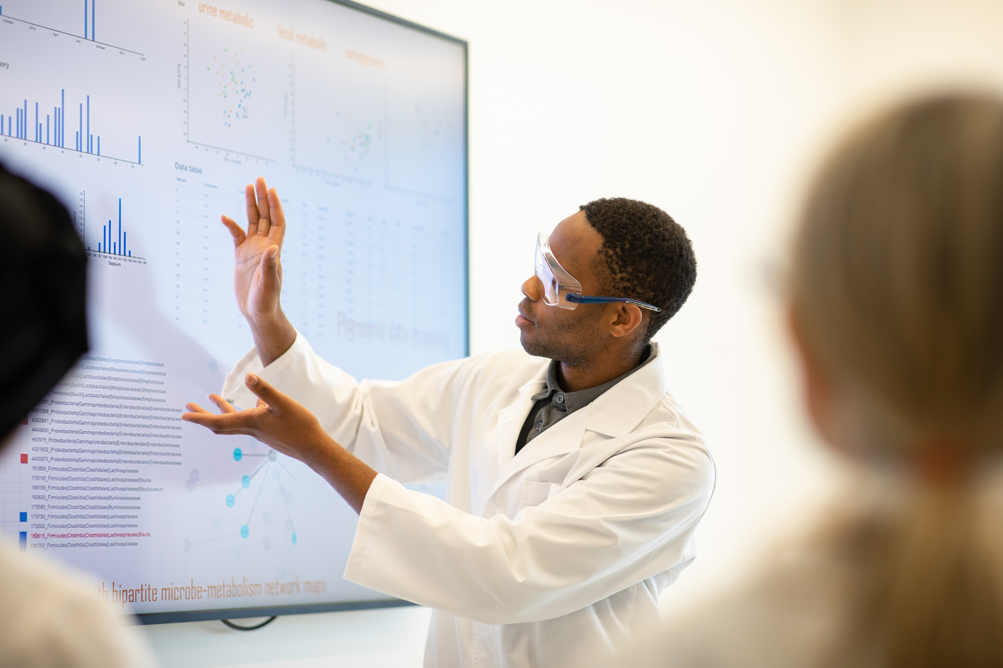 Male medical scientist gesturing and describing data on a screen during a meeting